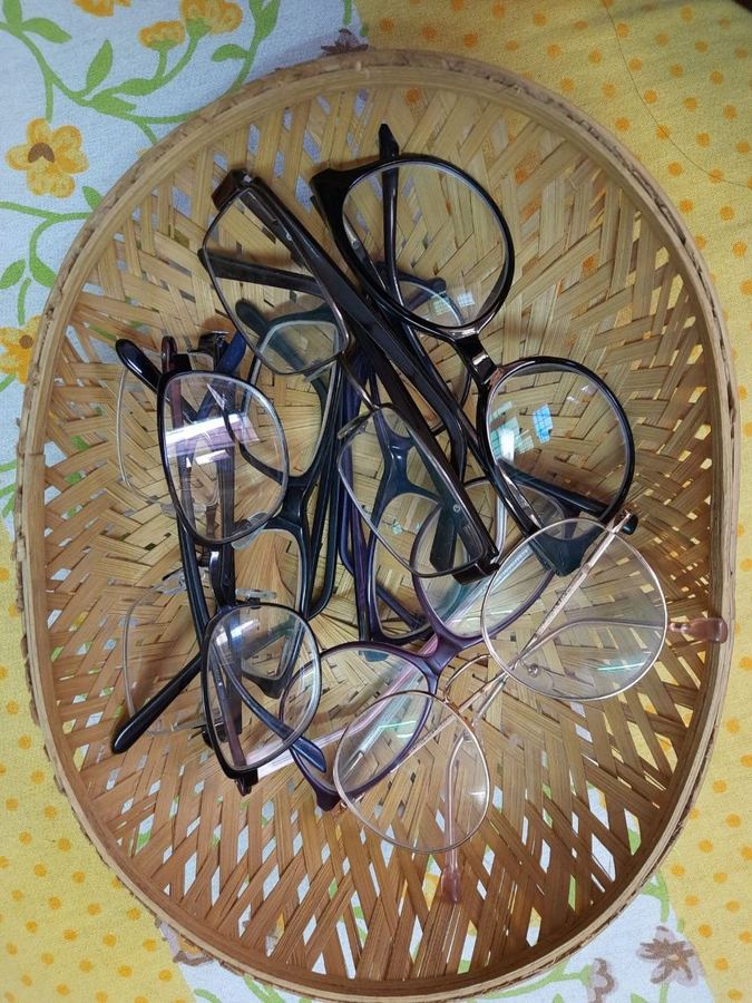 A woven basket holding a dozen used prescription glasses collected by the Specxy team